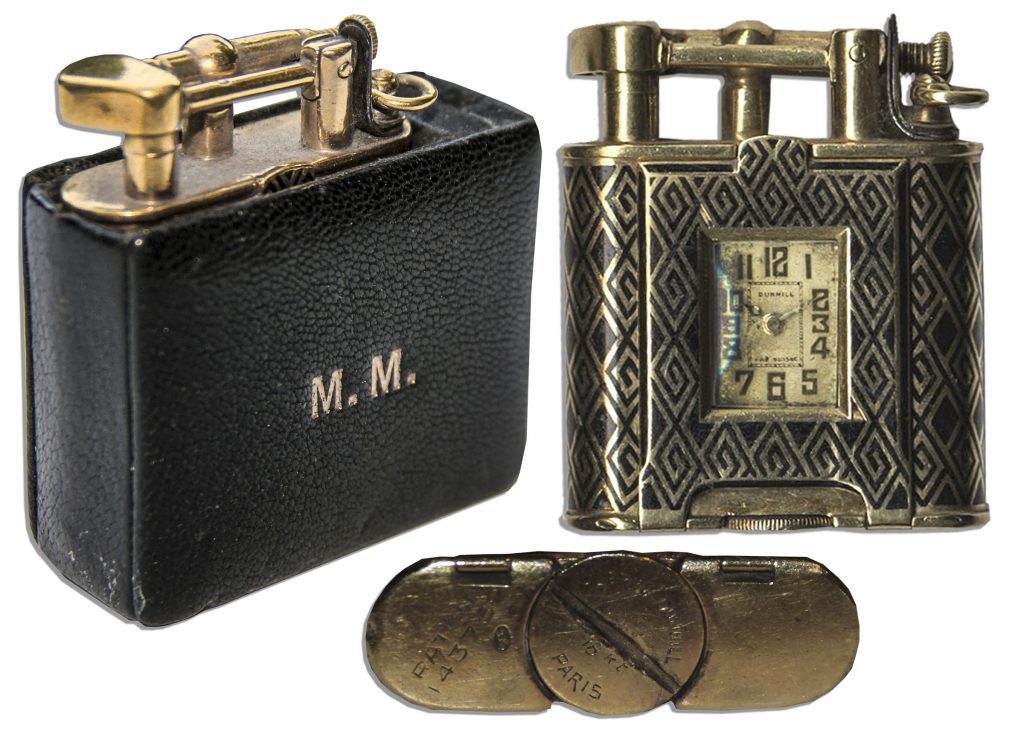 Cigarette lighter with timepiece housed in a leather case. Case has Marilyn Monroe's initials