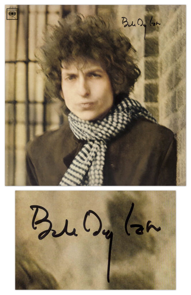 Blurry color image of Bob Dylan wearing a dark coat and gingham scarf. Dylan signs upper right.